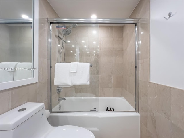 full bathroom with toilet, tile walls, and combined bath / shower with glass door