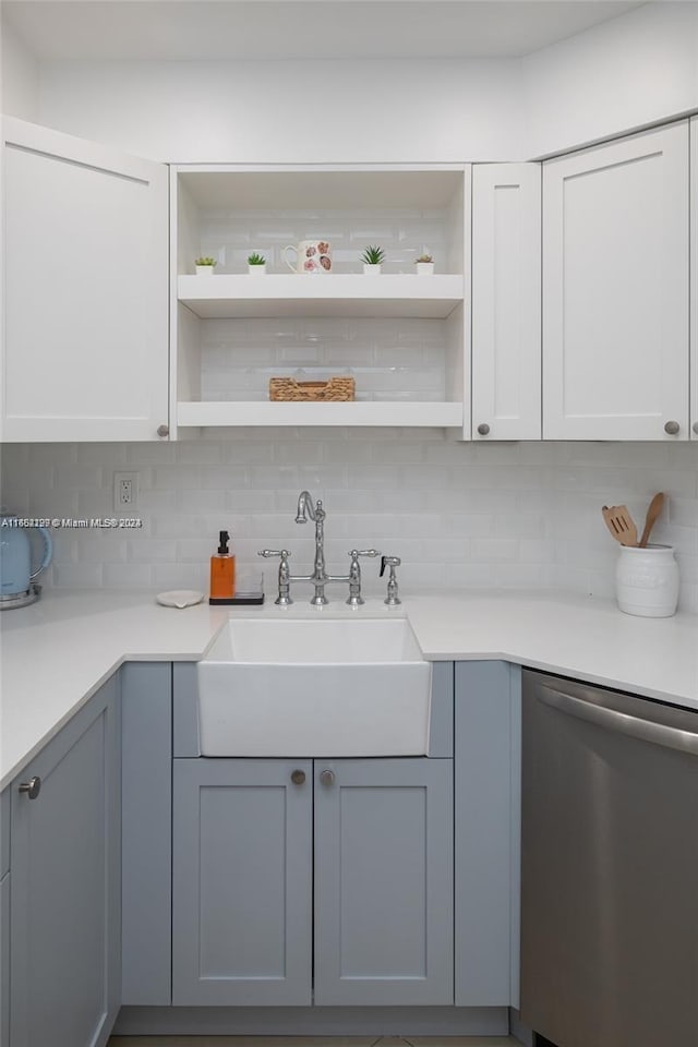 kitchen with a sink, open shelves, stainless steel dishwasher, backsplash, and light countertops