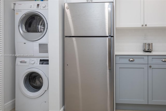 washroom featuring laundry area, stacked washing maching and dryer, and baseboards