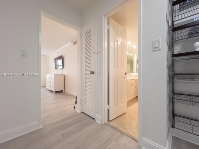 hallway featuring light wood finished floors, visible vents, and baseboards