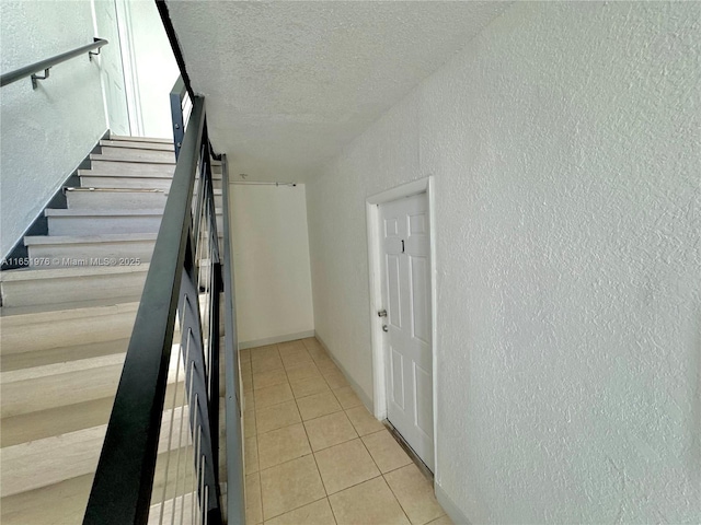 stairway with tile patterned floors and a textured ceiling