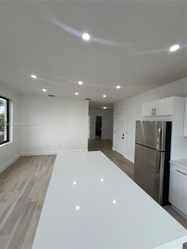 kitchen featuring white cabinets, wood-type flooring, and stainless steel refrigerator