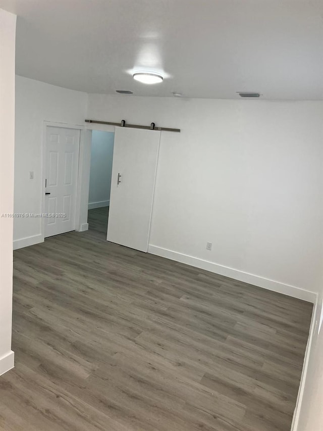 spare room featuring a barn door and dark hardwood / wood-style flooring