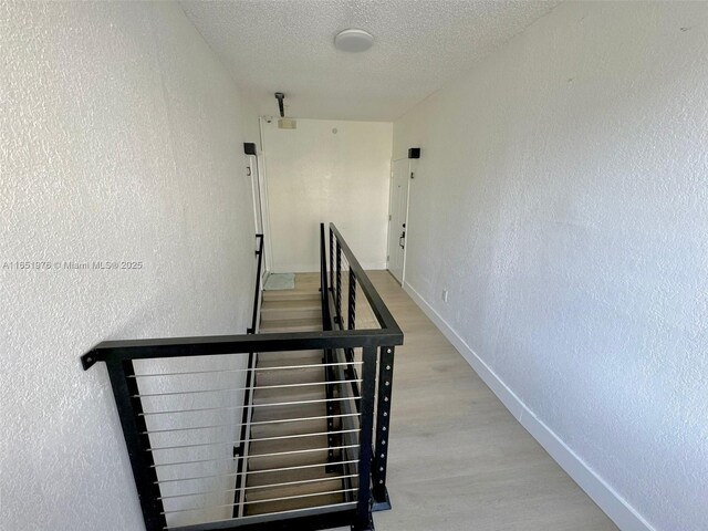 stairway featuring wood-type flooring and a textured ceiling