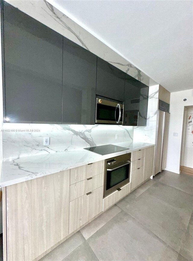 kitchen with light stone counters, light brown cabinets, and appliances with stainless steel finishes