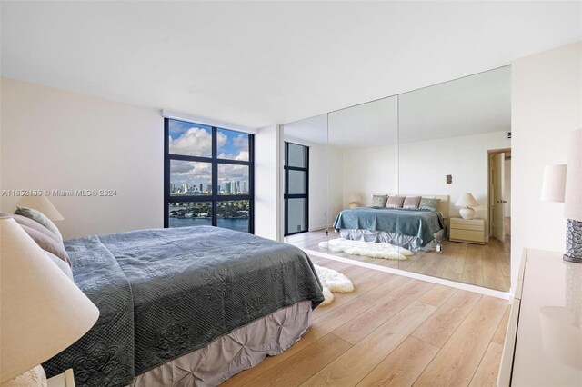 bedroom with light wood-type flooring and a wall of windows