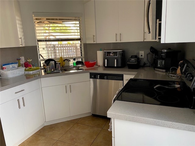 kitchen with electric stove, white cabinetry, light tile patterned floors, dishwasher, and sink