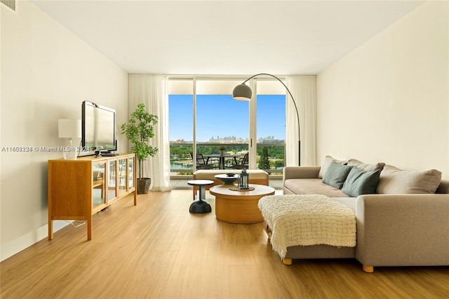 living room featuring light wood-type flooring and floor to ceiling windows