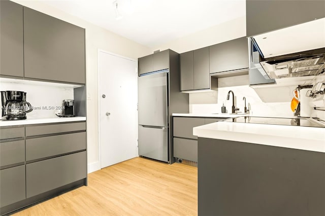 kitchen with light wood-type flooring, stainless steel fridge, and gray cabinets