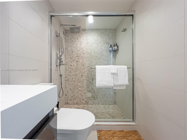 bathroom with tile patterned floors, walk in shower, toilet, tile walls, and vanity