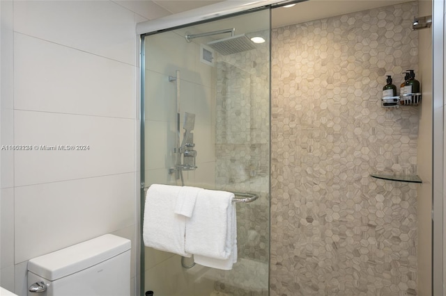 bathroom featuring toilet and a shower with shower door