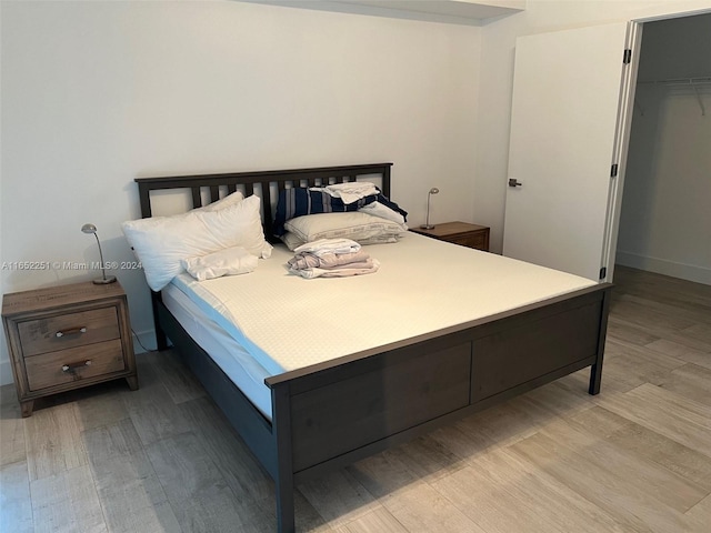 bedroom with a spacious closet, light hardwood / wood-style flooring, and a closet