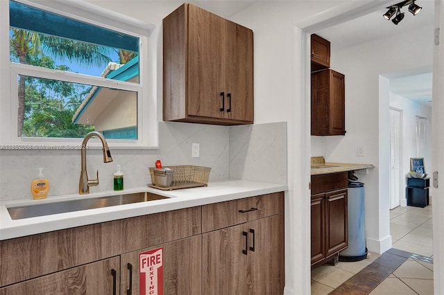 kitchen with backsplash, light tile patterned floors, and sink