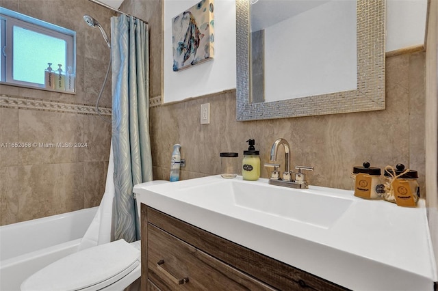 full bathroom with vanity, toilet, tile walls, and shower / bathtub combination with curtain