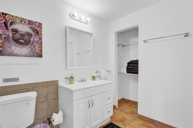 bathroom with vanity, toilet, tile walls, and tile patterned floors