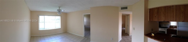 kitchen featuring visible vents, a textured ceiling, freestanding refrigerator, light tile patterned floors, and baseboards