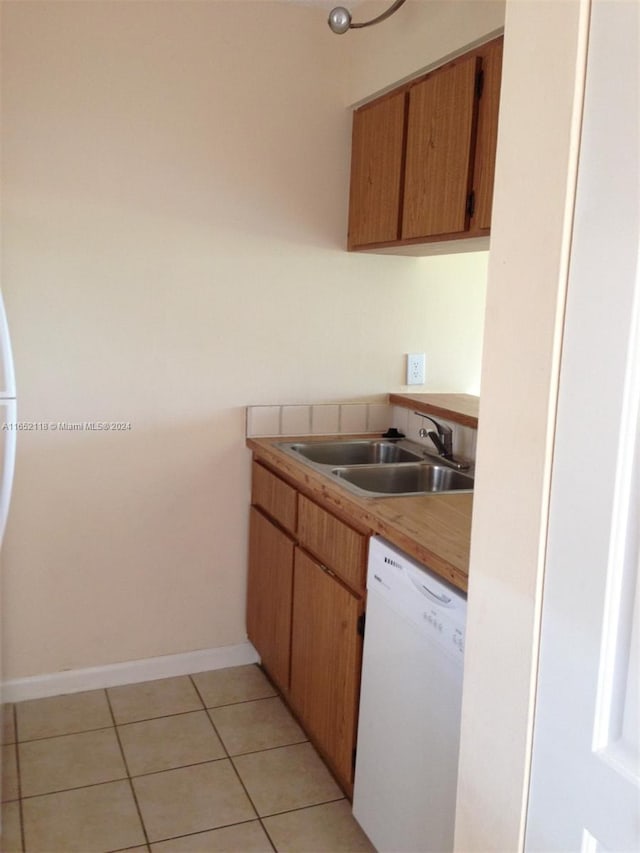 kitchen with light tile patterned floors, white dishwasher, and sink