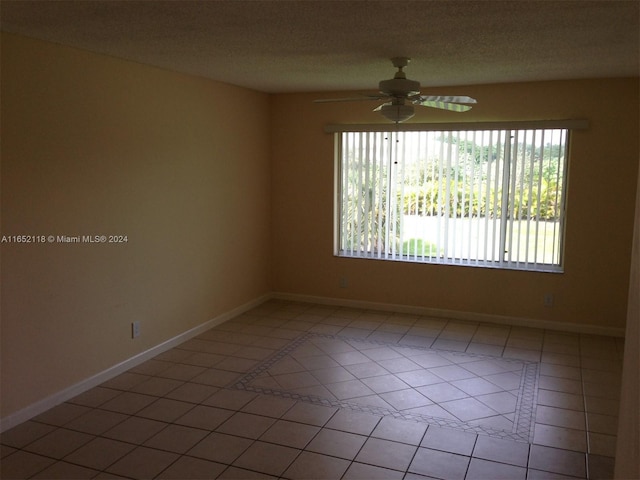 tiled spare room featuring a textured ceiling and ceiling fan