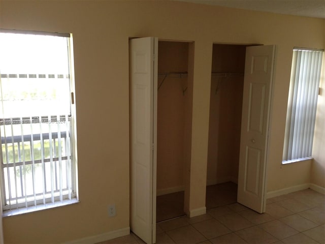 10127 Twin Lakes Dr Unit 24-J, Coral Springs, FL 33071 - unfurnished bedroom featuring light tile patterned floors, baseboards, and two closets