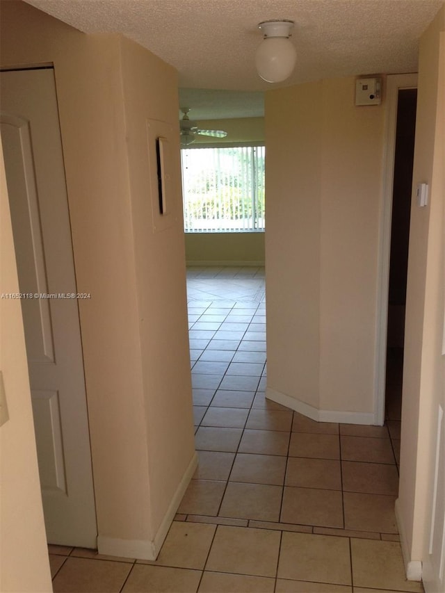 corridor with light tile patterned floors and a textured ceiling