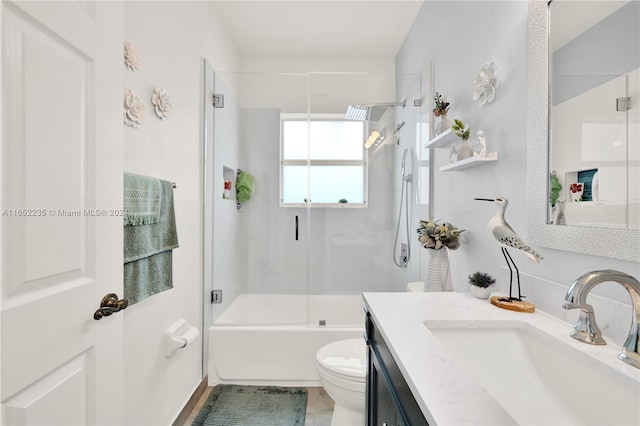 full bathroom with combined bath / shower with glass door, vanity, and toilet