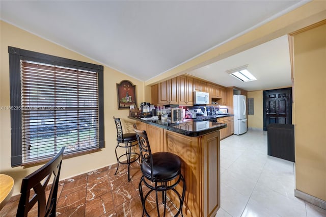 kitchen with a breakfast bar area, vaulted ceiling, stainless steel stove, kitchen peninsula, and sink