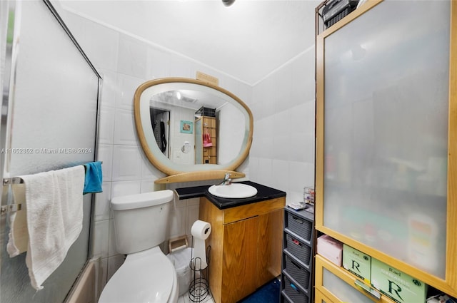 full bathroom with tile walls, toilet, vanity, and combined bath / shower with glass door