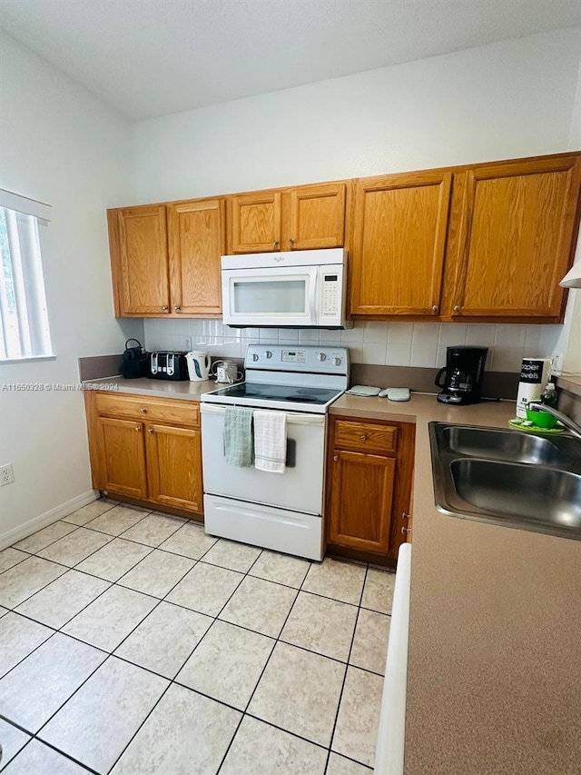 kitchen with light tile patterned flooring, sink, white appliances, and tasteful backsplash