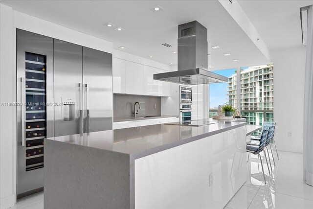 16500 Collins Ave Unit 2451, Sunny Isles Beach, FL 33160 - kitchen with modern cabinets, island exhaust hood, stainless steel appliances, white cabinets, and a wall of windows