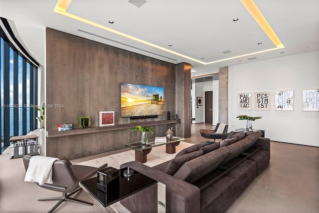 living room featuring concrete flooring and a raised ceiling