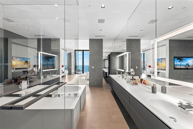 kitchen featuring sink, hanging light fixtures, a water view, light tile patterned floors, and a wall of windows