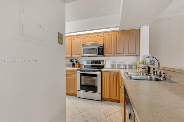 kitchen with a textured ceiling, stainless steel appliances, sink, and light tile patterned flooring