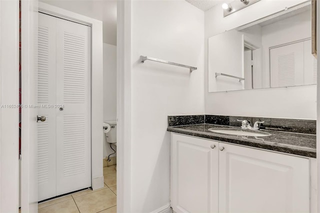 bathroom featuring tile patterned flooring, toilet, and vanity