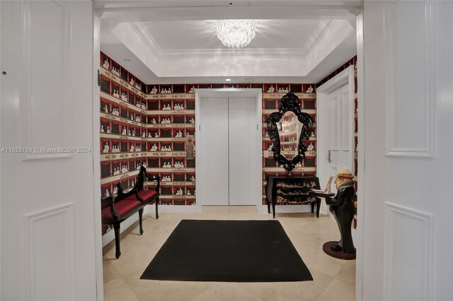 interior space featuring ornamental molding, a raised ceiling, and a chandelier