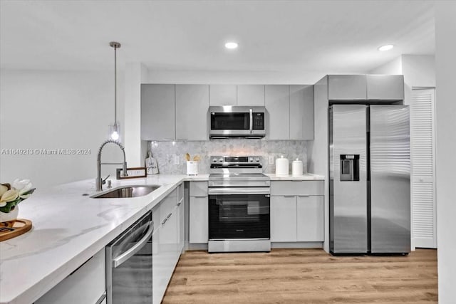 kitchen featuring gray cabinetry, sink, stainless steel appliances, decorative light fixtures, and light wood-type flooring