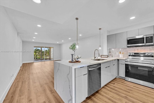 kitchen featuring pendant lighting, sink, stainless steel appliances, and light wood-type flooring