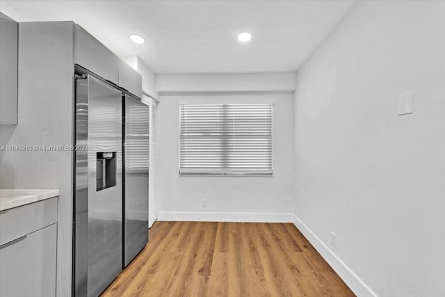 interior space with stainless steel fridge with ice dispenser, gray cabinets, and light wood-type flooring