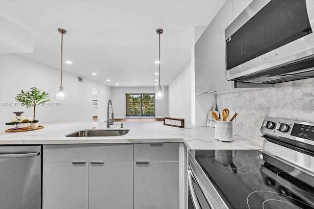 kitchen featuring light stone counters, sink, hanging light fixtures, and appliances with stainless steel finishes