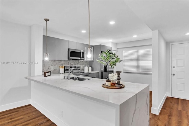 kitchen with hardwood / wood-style floors, gray cabinets, decorative light fixtures, kitchen peninsula, and stainless steel appliances