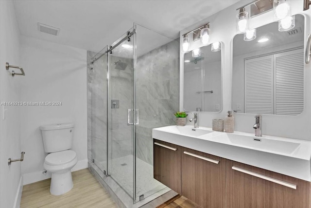 bathroom featuring hardwood / wood-style floors, vanity, toilet, and a shower with shower door