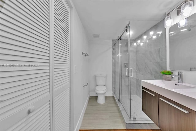 bathroom featuring hardwood / wood-style floors, vanity, toilet, and an enclosed shower