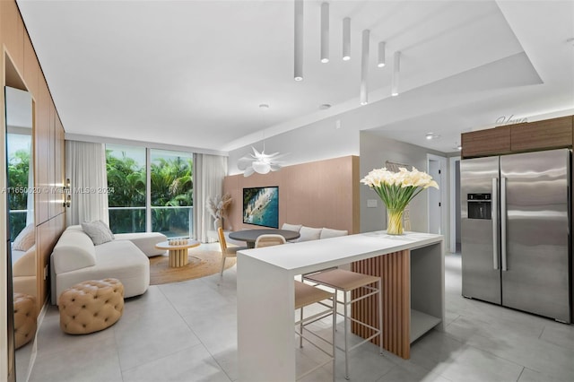 kitchen with expansive windows, a breakfast bar area, and stainless steel fridge with ice dispenser