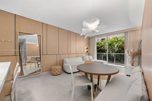 dining area with light tile patterned floors, ceiling fan, and wooden walls