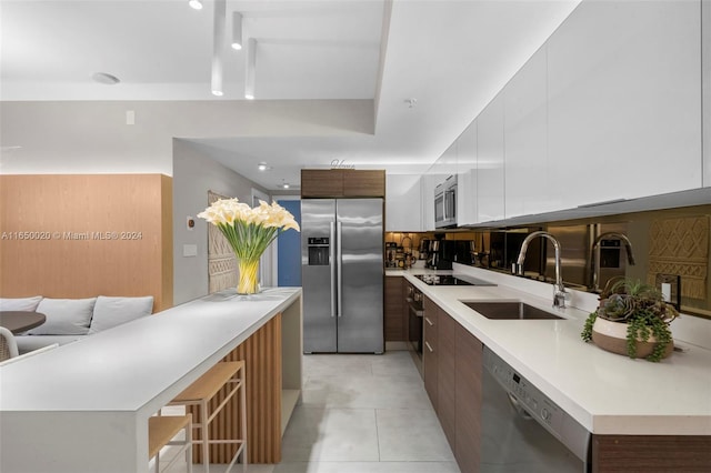 kitchen with white cabinetry, sink, a breakfast bar, appliances with stainless steel finishes, and light tile patterned flooring