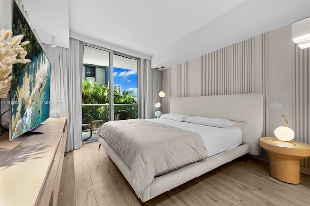 bedroom with floor to ceiling windows, light hardwood / wood-style floors, and access to exterior