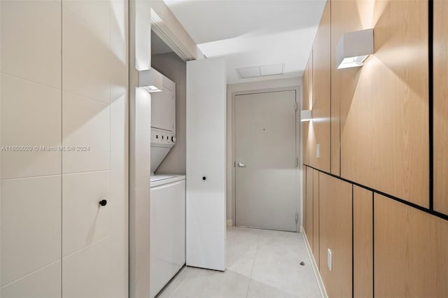 washroom featuring tile walls, light tile patterned floors, and stacked washer / drying machine