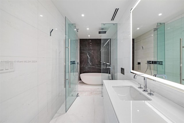 bathroom with vanity, separate shower and tub, and tile walls