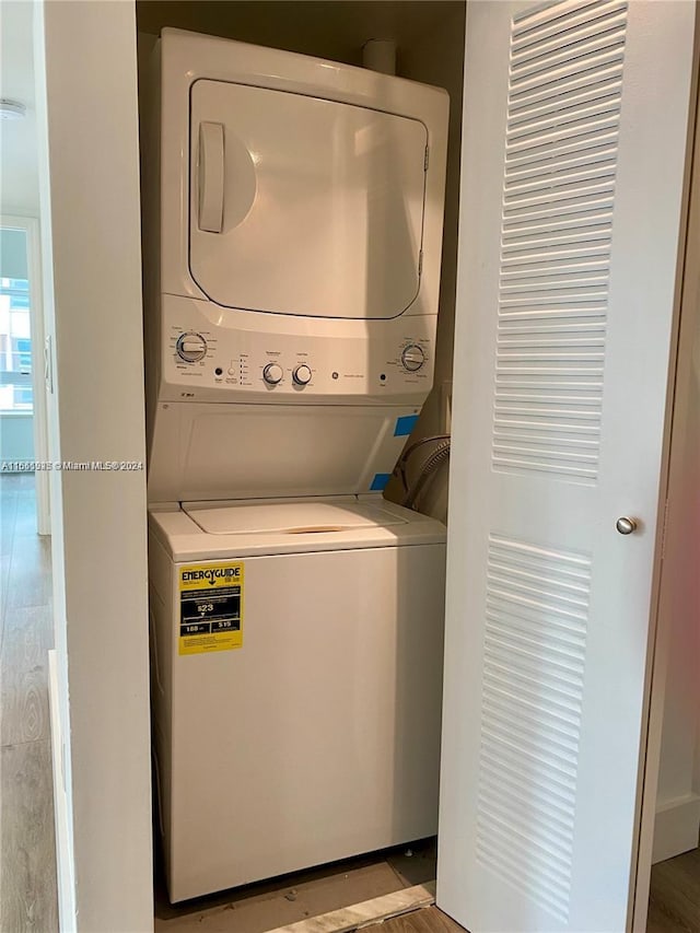 laundry area with stacked washer and clothes dryer and light hardwood / wood-style floors