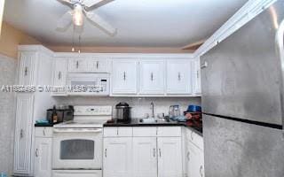 kitchen with ceiling fan, sink, white appliances, and white cabinets