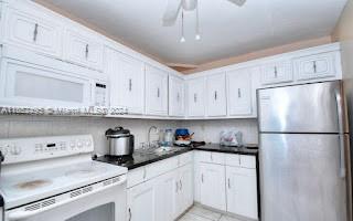 kitchen featuring ceiling fan, white appliances, and white cabinets